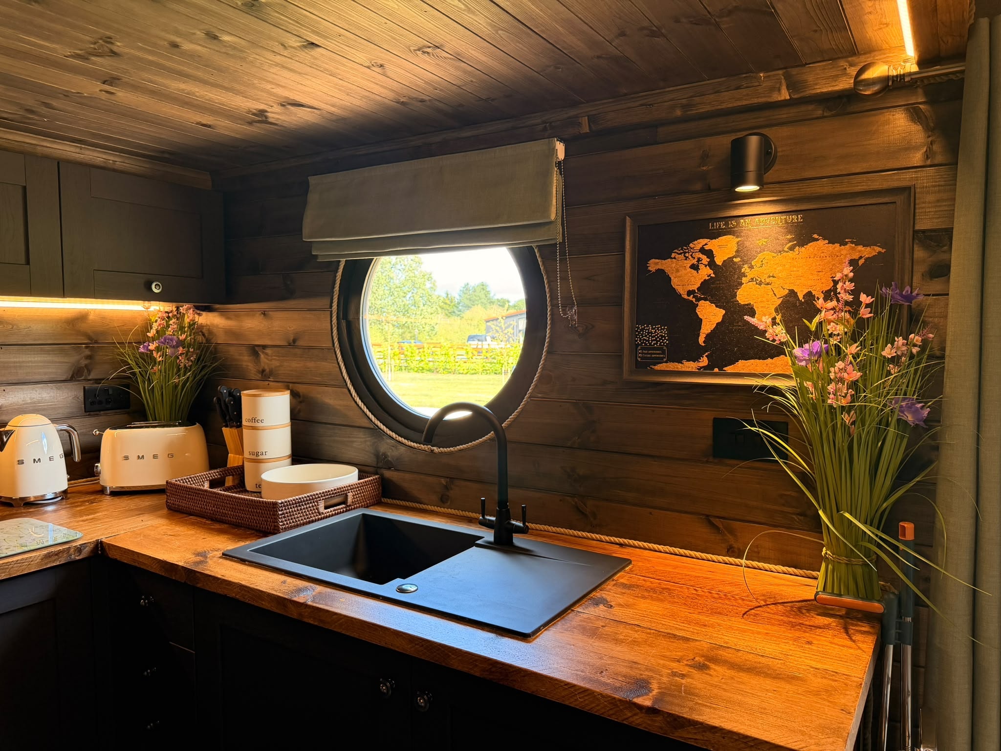 Elmtree Cabins kitchen with dark cabinetry and porthole window